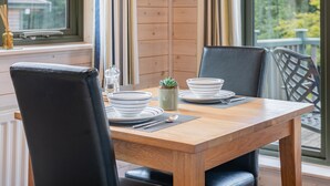 Een eettafel met stoelen, een plantje en een raam met uitzicht op bomen.