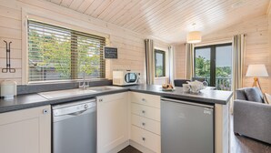 Een compacte keuken met een vaatwasser, magnetron en spoelbak. Er zijn kastjes en een aanrecht.