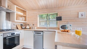 Une cuisine moderne avec des meubles blancs, des appareils en acier inoxydable et un plafond en bois.