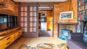 A wooden interior with a television, a fireplace, and a kitchen area.