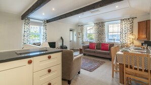 A modern kitchen with a central island, a dining area with a wooden table, and a living room with a sofa and a fireplace. - Ben Place Cottage -  A short stroll from Grasmere Village (Grasmere)