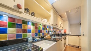 A kitchen with a colorful tile backsplash, a black countertop, and white cabinets. - Ben Place Cottage -  A short stroll from Grasmere Village (Grasmere)