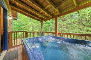 A hot tub under a wooden deck with a view of a forest. - Log Cabin, Dog Friendly, Minutes to Attractions, Hot tub, Fire-pit, Peaceful! (Sevierville)