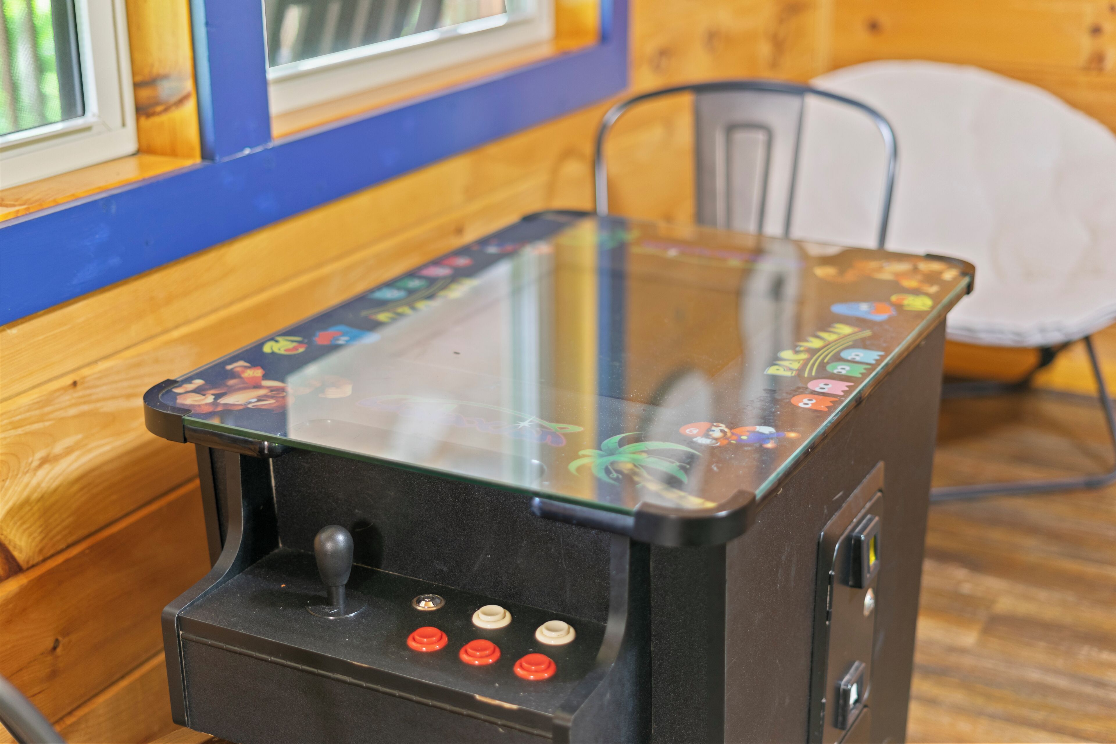 Un interior de madera con una máquina arcade de tapa de vidrio.
