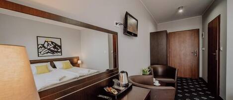 Una habitación de hotel con cama, escritorio, silla, televisor y puerta.