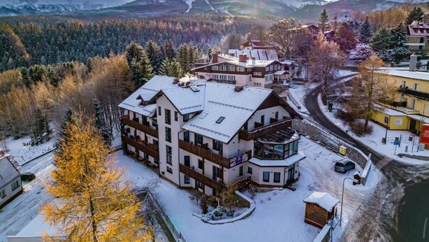 A multi-story hotel with a ski lift in the background, surrounded by snow-covered trees and mountains. - Karpacki&SPA z Restauracją  (Karpacz)