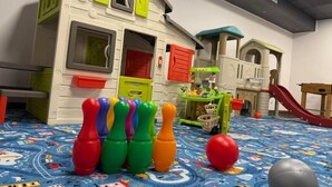 A play area with a playhouse, colorful bottles, and a ball on a patterned floor. - Karpacki&SPA z Restauracją  (Karpacz)