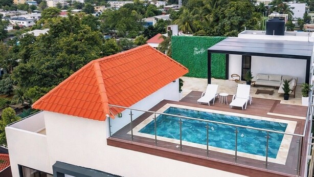 En modern byggnad med en pool på taket, vita väggar och ett rött tak.