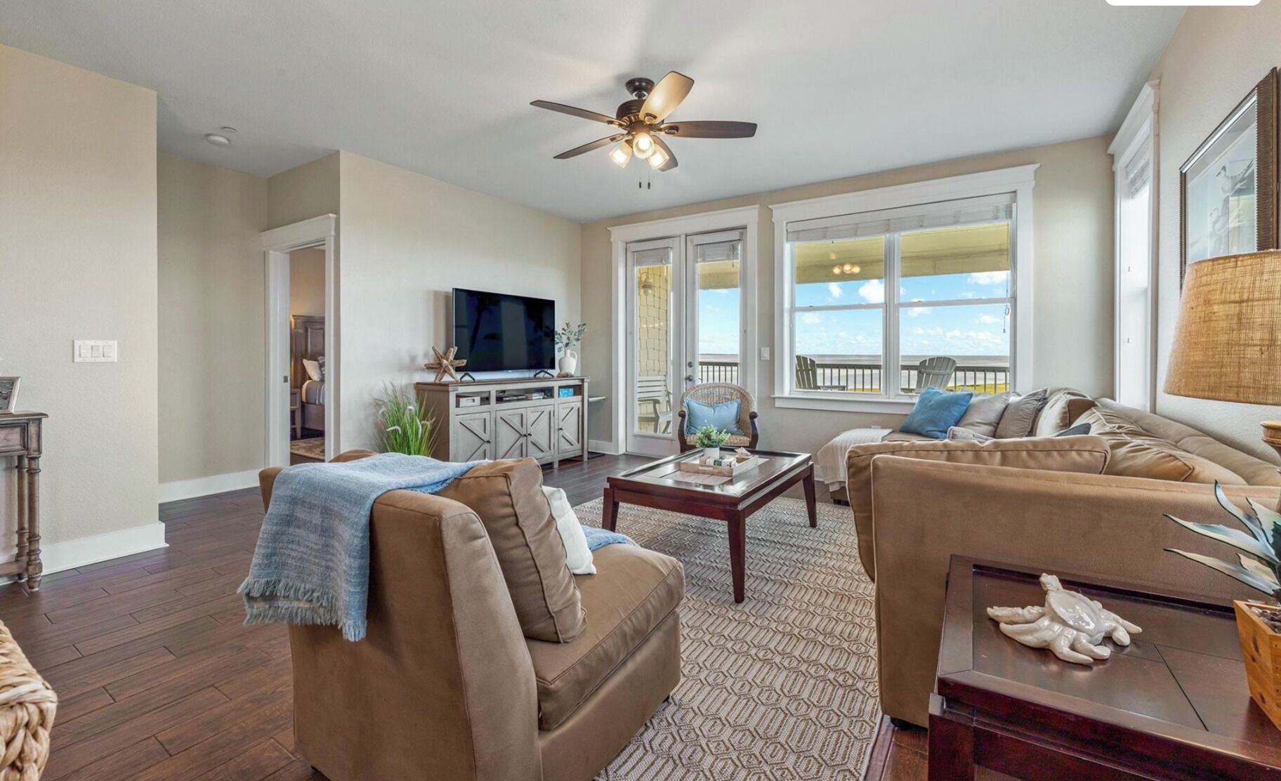 A living room with a sofa, a coffee table, a TV, and a ceiling fan.