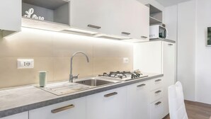 Eine moderne Küche mit weißen Schränken, einer Edelstahl-Spüle, einem Gasherd und einer Mikrowelle auf der Arbeitsfläche.