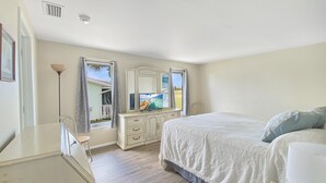 A bedroom with a bed, a dresser, a mirror, and a window with a view. - Sun Saver, Sleeps 6, full refund*, NO pool. (Rotonda West)