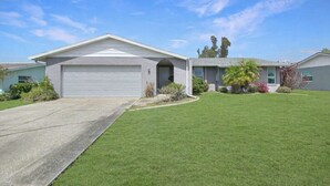 A single-story house with a garage, a well-maintained lawn, and a clear sky. - Sun Saver, Sleeps 6, full refund*, NO pool. (Rotonda West)