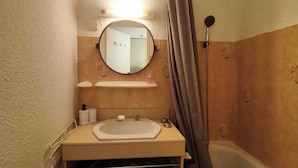 Un baño con lavamanos, espejo, toallero y cortina de ducha.