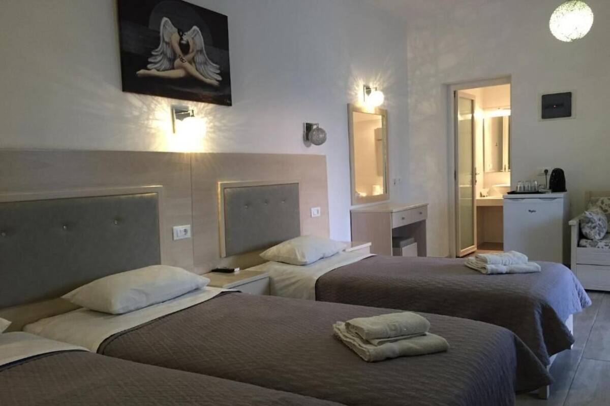 Une chambre d’hôtel avec deux lits, un miroir, un petit bureau et une kitchenette.