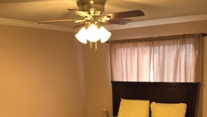 A bedroom with a bed, a dresser, a ceiling fan, and a patterned rug.