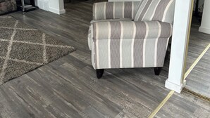 A living room with a striped armchair, a dining table, and a rug.