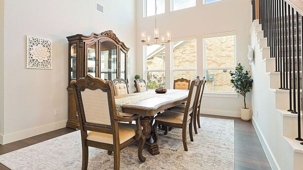 A dining room with a wooden table and chairs, a decorative mirror, and a chandelier.