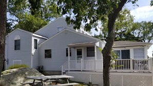 A two-story house with a porch, a picnic table, and a large rock in the yard. - Awesome Oceanfront 4-bedroom watersports cottage in Mystic (Stonington)
