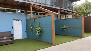 A modern building with a blue exterior, a wooden deck, and a green artificial lawn. - Tisza Gyöngye Apartmanok (Szeged)