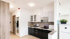 A modern kitchen with black cabinets, a white countertop, and a built-in stove. - Tisza Gyöngye Apartmanok (Szeged)