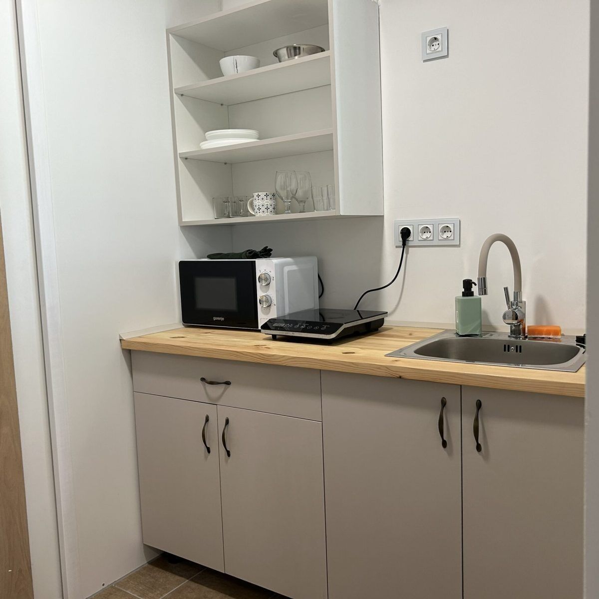 Cocina compacta con microondas, tostadora y lavabo con grifo.