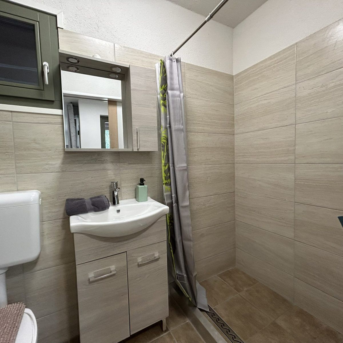 Un baño con inodoro, lavamanos, espejo y cortina de ducha.