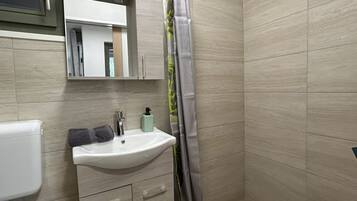 Un baño con inodoro, lavamanos, espejo y cortina de ducha.