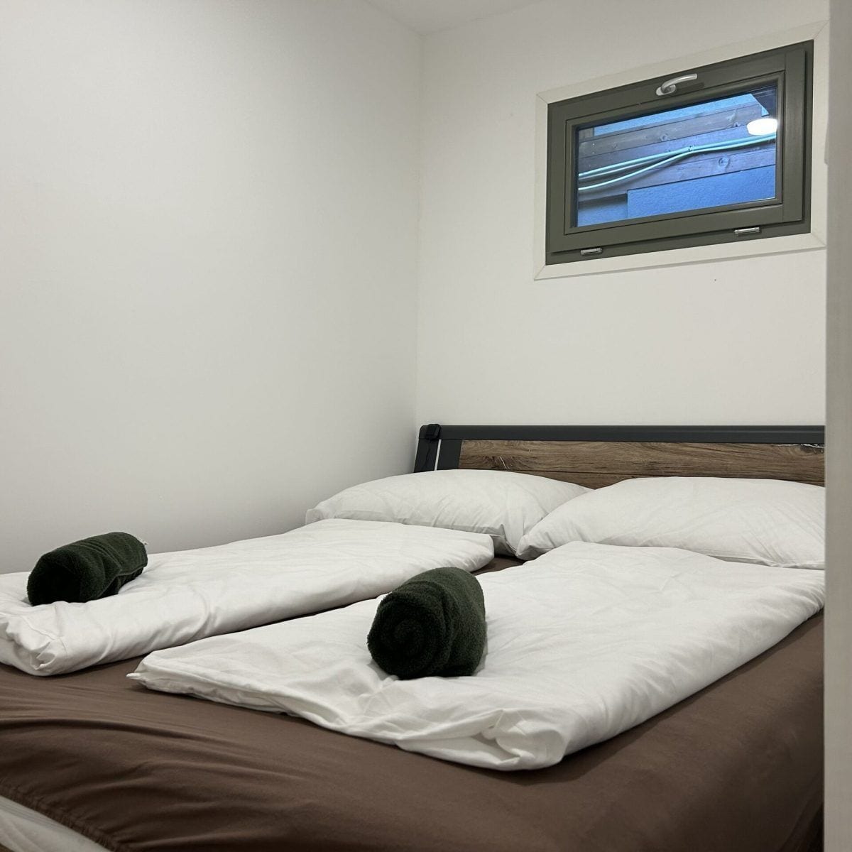 A hotel room with a single bed, white bedding, and a television mounted on the wall.
