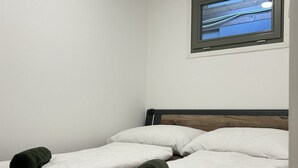 A hotel room with a single bed, white bedding, and a television mounted on the wall. - Tisza Gyöngye Apartmanok (Szeged)