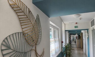 Un pasillo con una escalera espiral, una planta y un cartel que indica una salida.