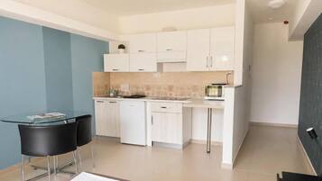 Une cuisine moderne avec des meubles blancs, une table ronde en verre et des chaises noires.