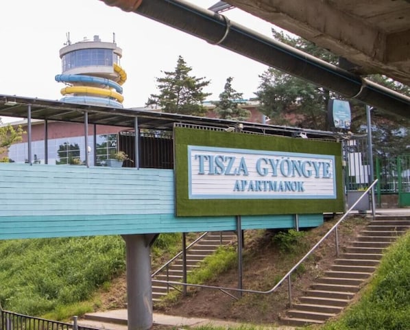 Une enseigne indiquant « TISZA GYONGYE APARTMANOK », avec un escalier menant à celle-ci.
