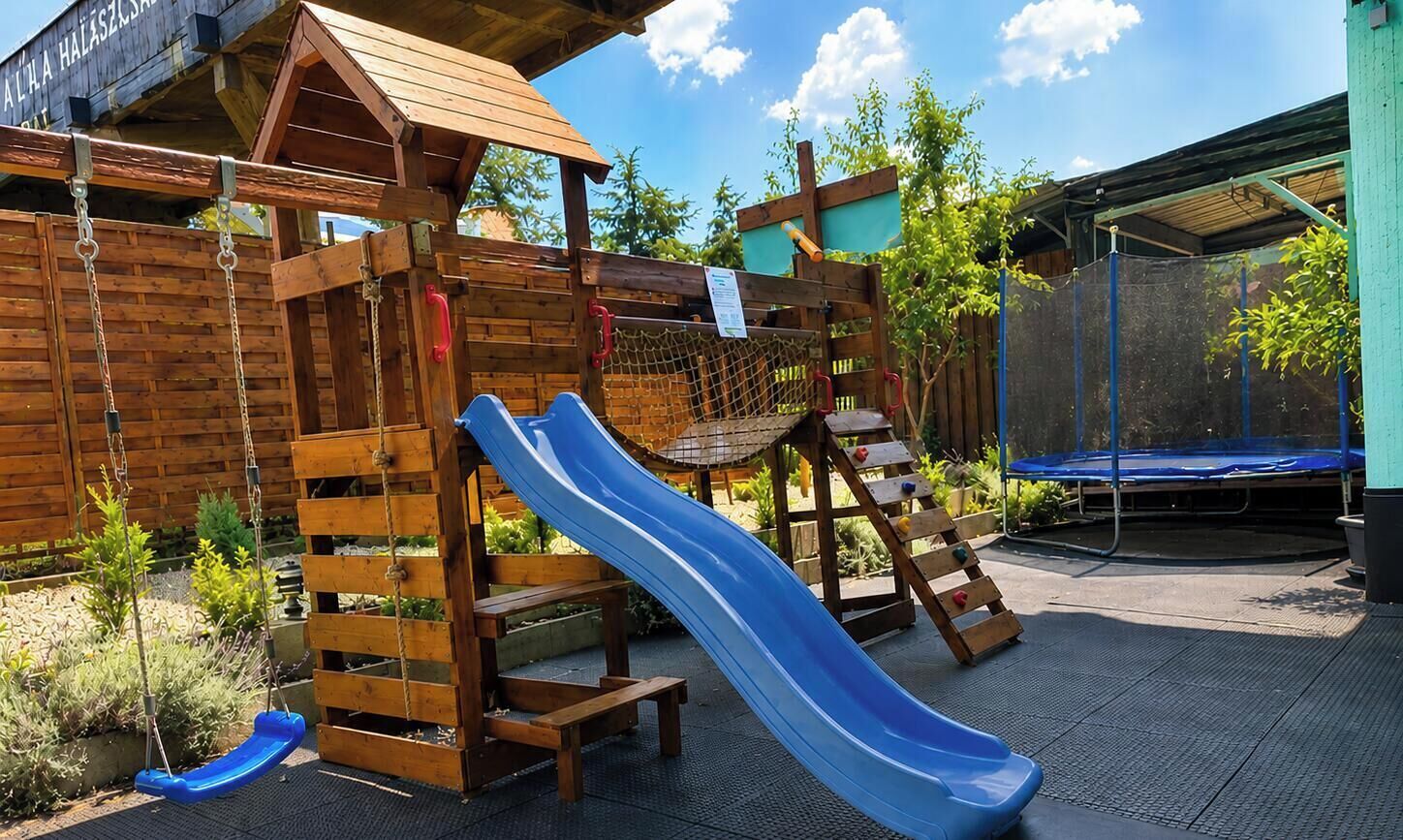 Una estructura de juego de madera con un tobogán, columpios y una escalera de escalada.