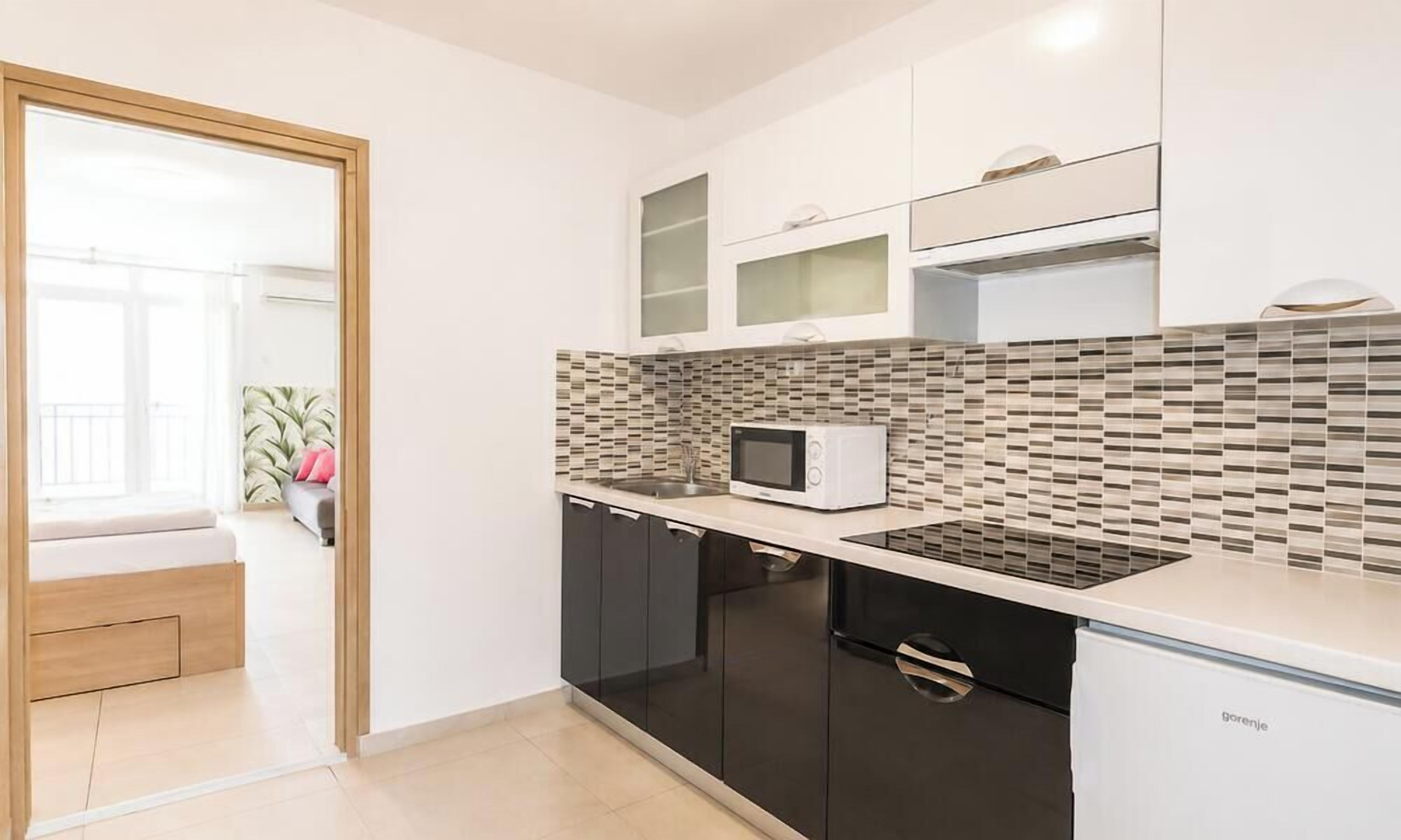 A modern kitchen with black cabinets, a white countertop, a microwave, and a built-in oven.