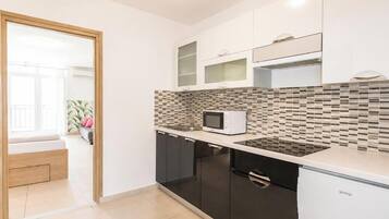 A modern kitchen with black cabinets, a white countertop, a microwave, and a built-in oven.