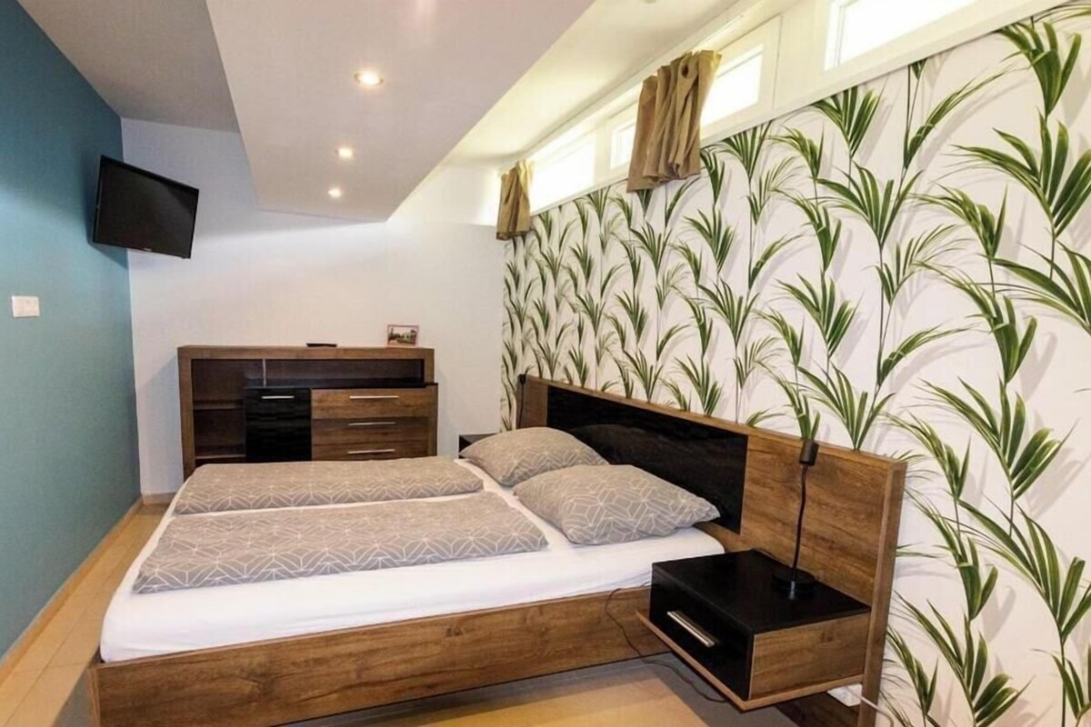 Ein Schlafzimmer mit Bett, Nachttischen, einem Fernseher und einer Wand mit Muster.
