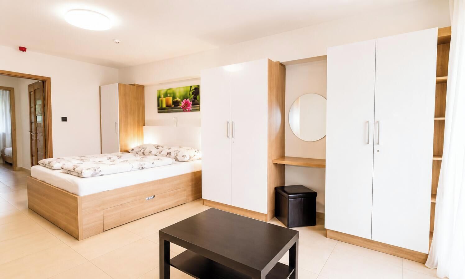Un dormitorio moderno con cama, armario y una pequeña mesa.