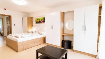 Un dormitorio moderno con cama, armario y una pequeña mesa.