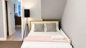 A bedroom with a bed, a bedside table, and a lamp.