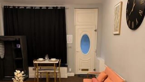 A living room with a sofa, a coffee table, a TV, and a clock on the wall.
