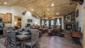A spacious living area with a dining table, sofas, and a fireplace. - Secluded Mountain Cabin with Hot Tub & Fire pit on 4 acres (Murphy)