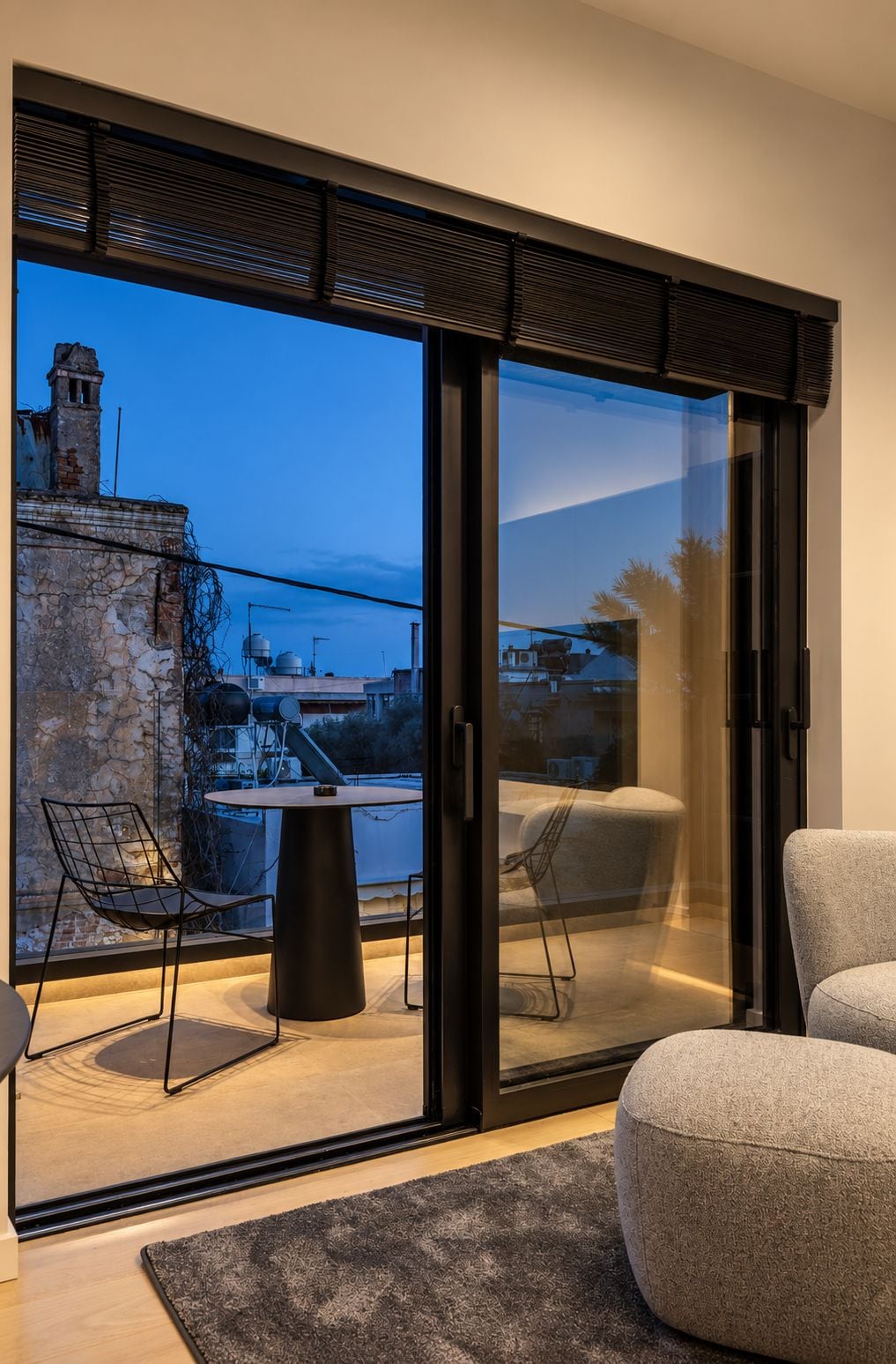 A modern interior with a sliding glass door leading to an outdoor area, a round table, two chairs, and a textured rug.