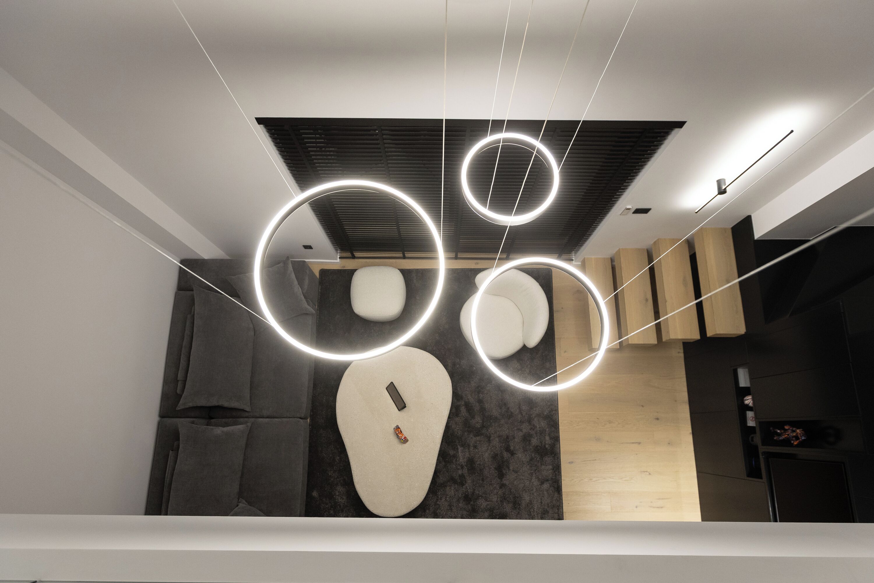 Un interno moderno con un design unico del soffitto, un divano minimalista e una parete d'accento in legno.