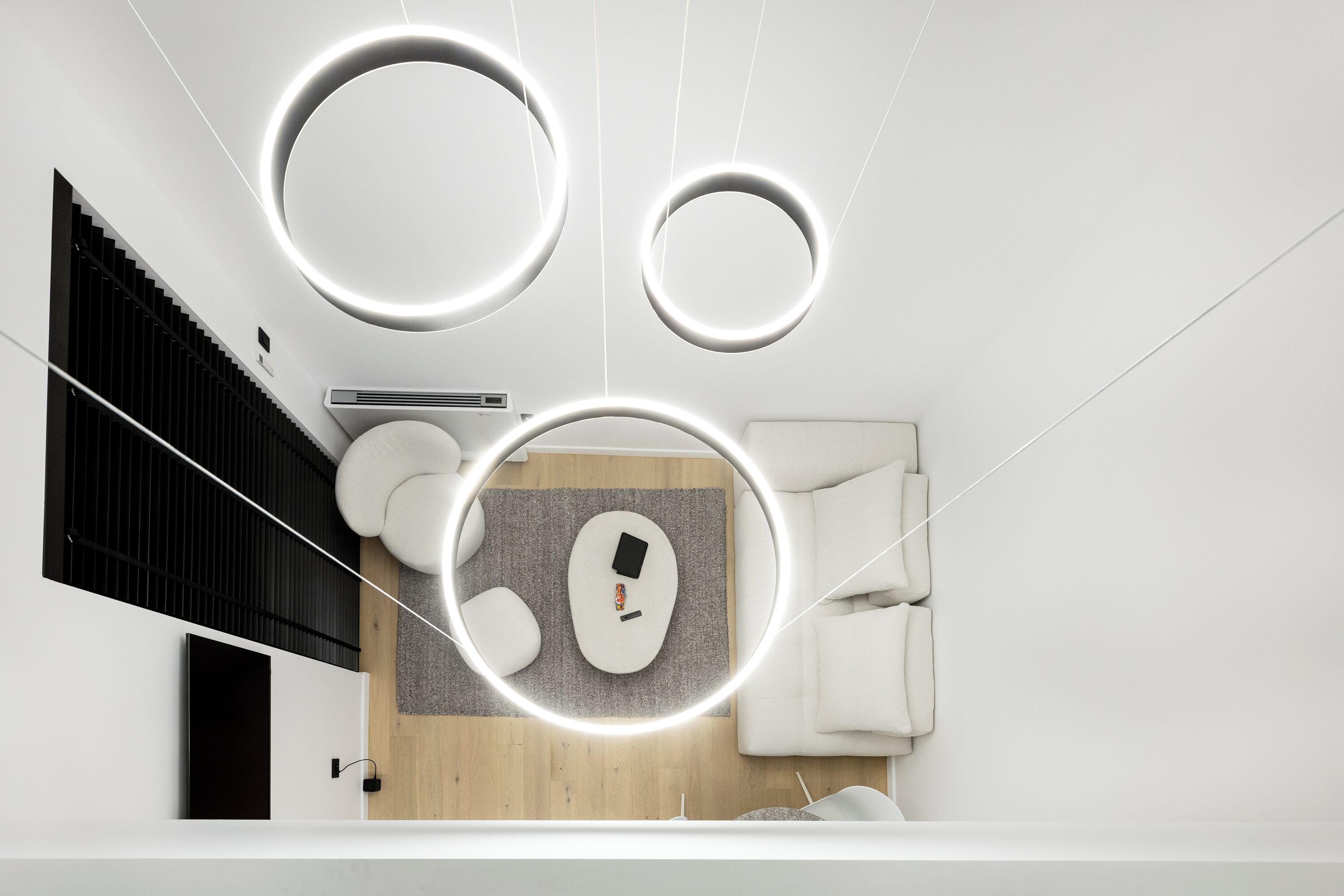 Un interior moderno con una escalera, luces de techo circulares, un sofá y una pequeña mesa.