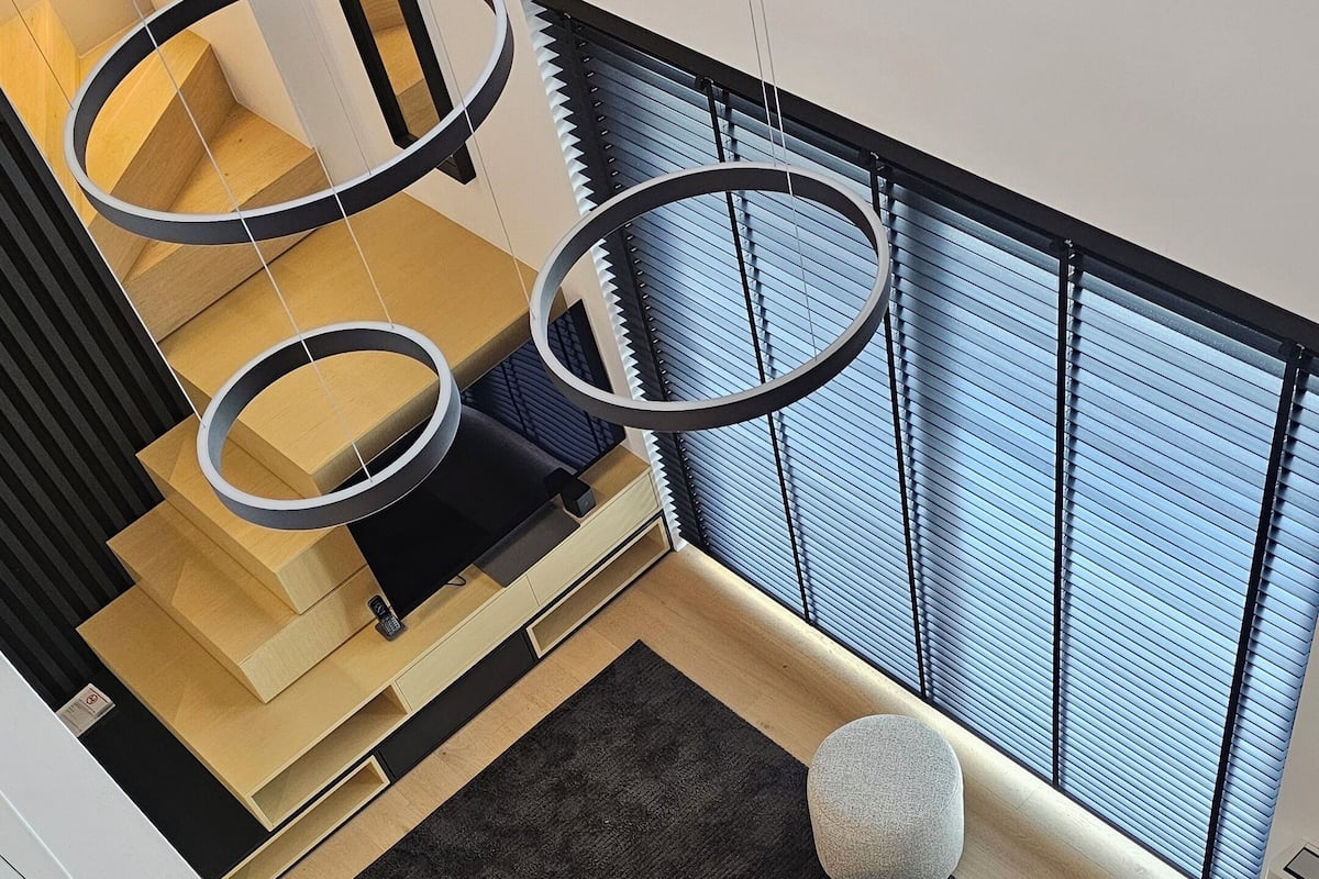 A modern interior with a staircase, a sofa, a small table, and a ring light.