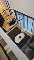 Un interior moderno con una escalera, un sofá, una mesita y una luz de aro.