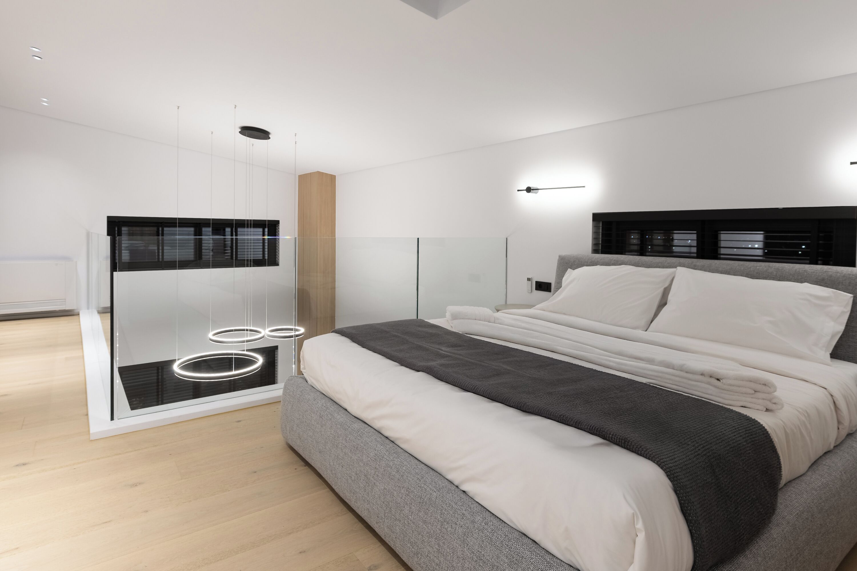 Un dormitorio moderno con una cama grande, un vestidor y una pared de vidrio.