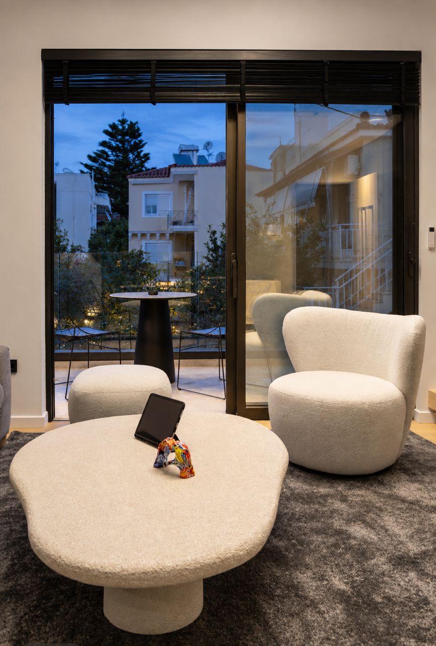 A modern living room with a round table, two chairs, and a laptop.