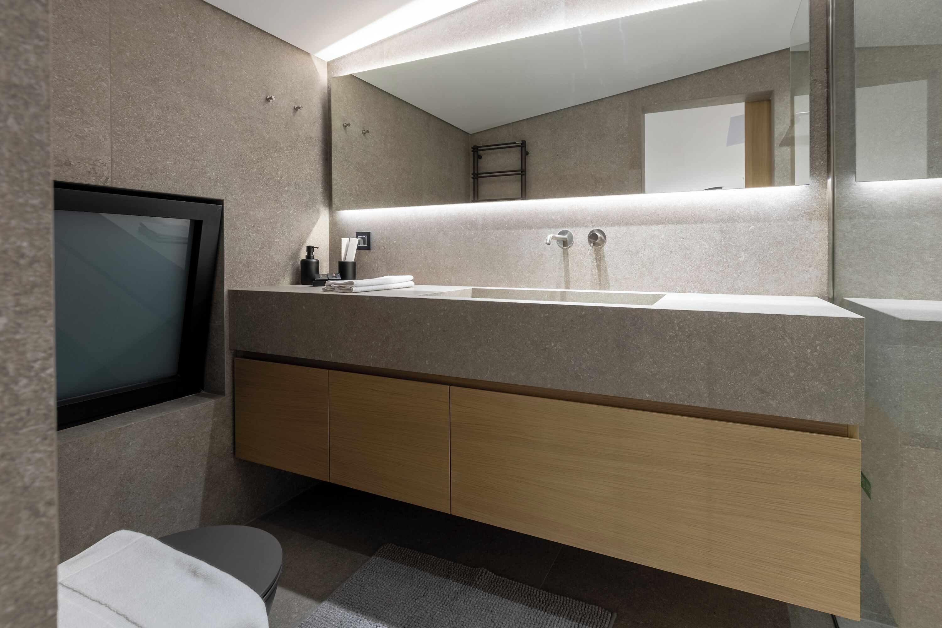 Une salle de bain moderne avec un grand miroir, un lavabo et des toilettes.