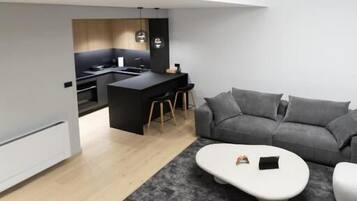 Un interior moderno con cocina, un sofá gris y una mesa de centro blanca.